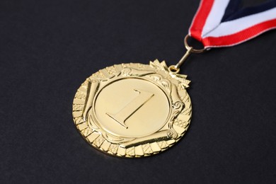 Photo of Golden medal with striped ribbon on black background, closeup