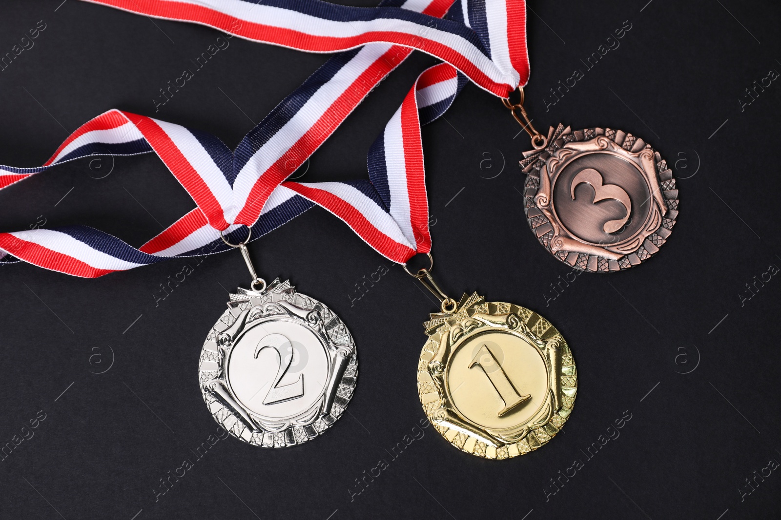 Photo of Golden, silver and bronze medals on black background, top view