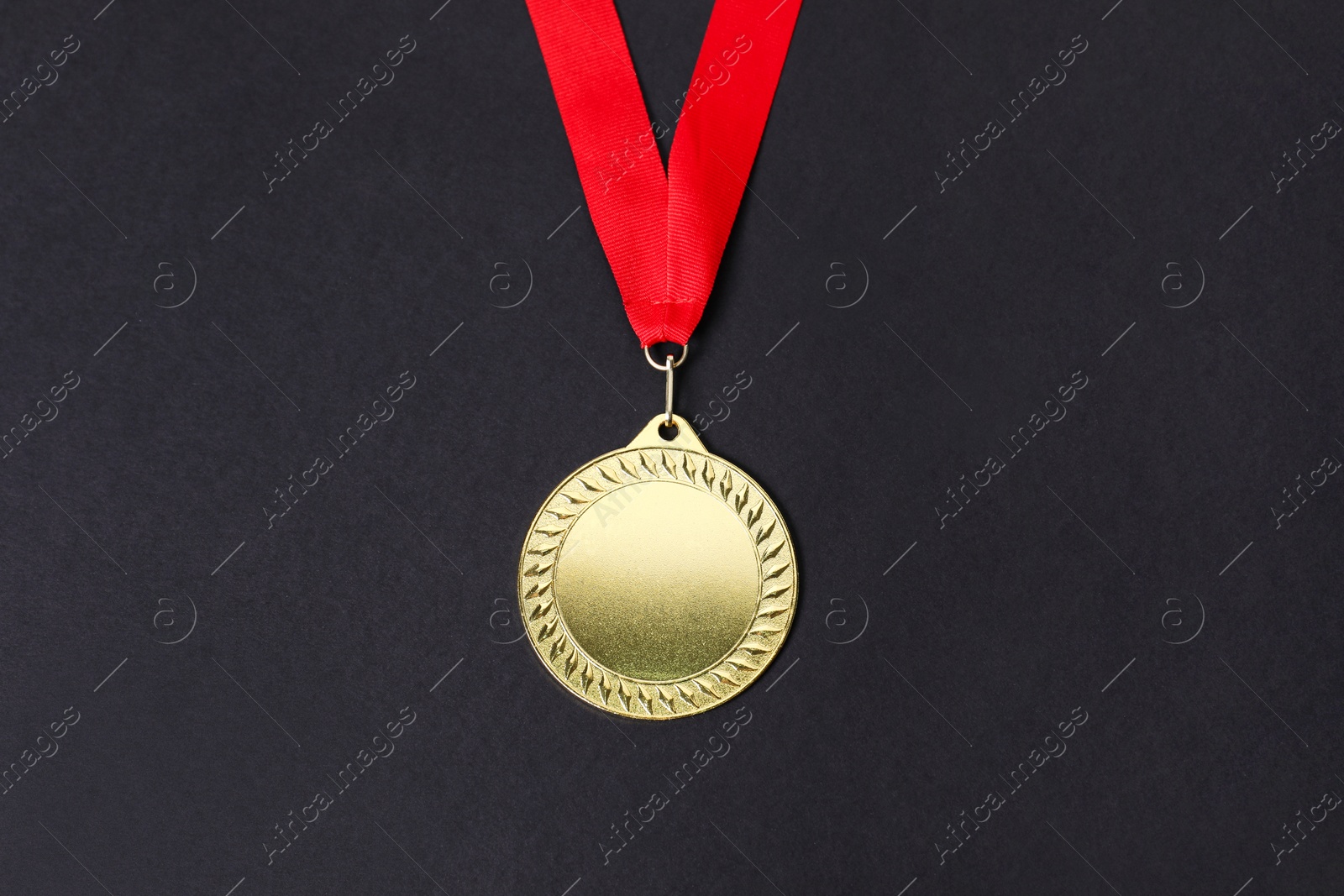 Photo of Golden medal with red ribbon on black background, top view