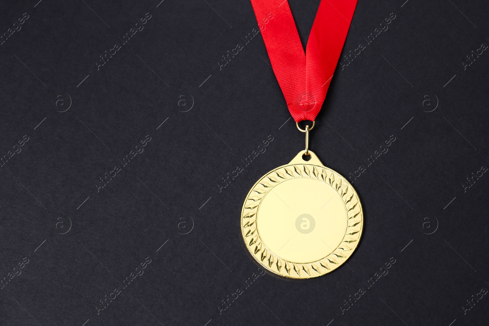 Photo of Golden medal with red ribbon on black background, space for text