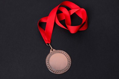 Photo of Bronze medal with red ribbon on black background, above view