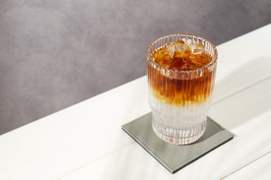 Refreshing espresso tonic drink on white wooden table, space for text