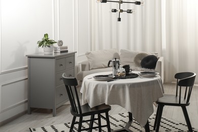 Photo of Stylish table setting with beautiful dishware and black chairs in dining room