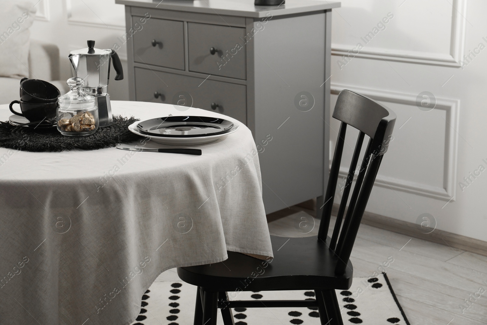 Photo of Stylish table setting with beautiful dishware and black chair in dining room