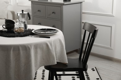 Photo of Stylish table setting with beautiful dishware and black chair in dining room