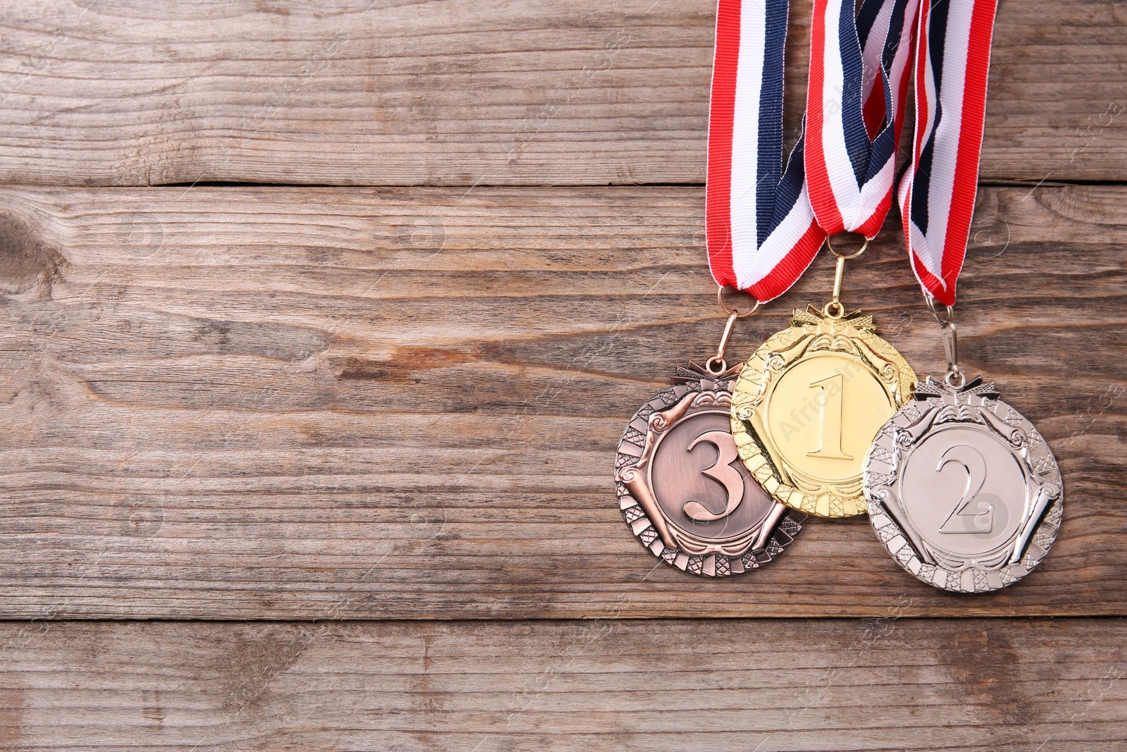 Photo of Golden, silver and bronze medals on wooden background, top view. Space for text