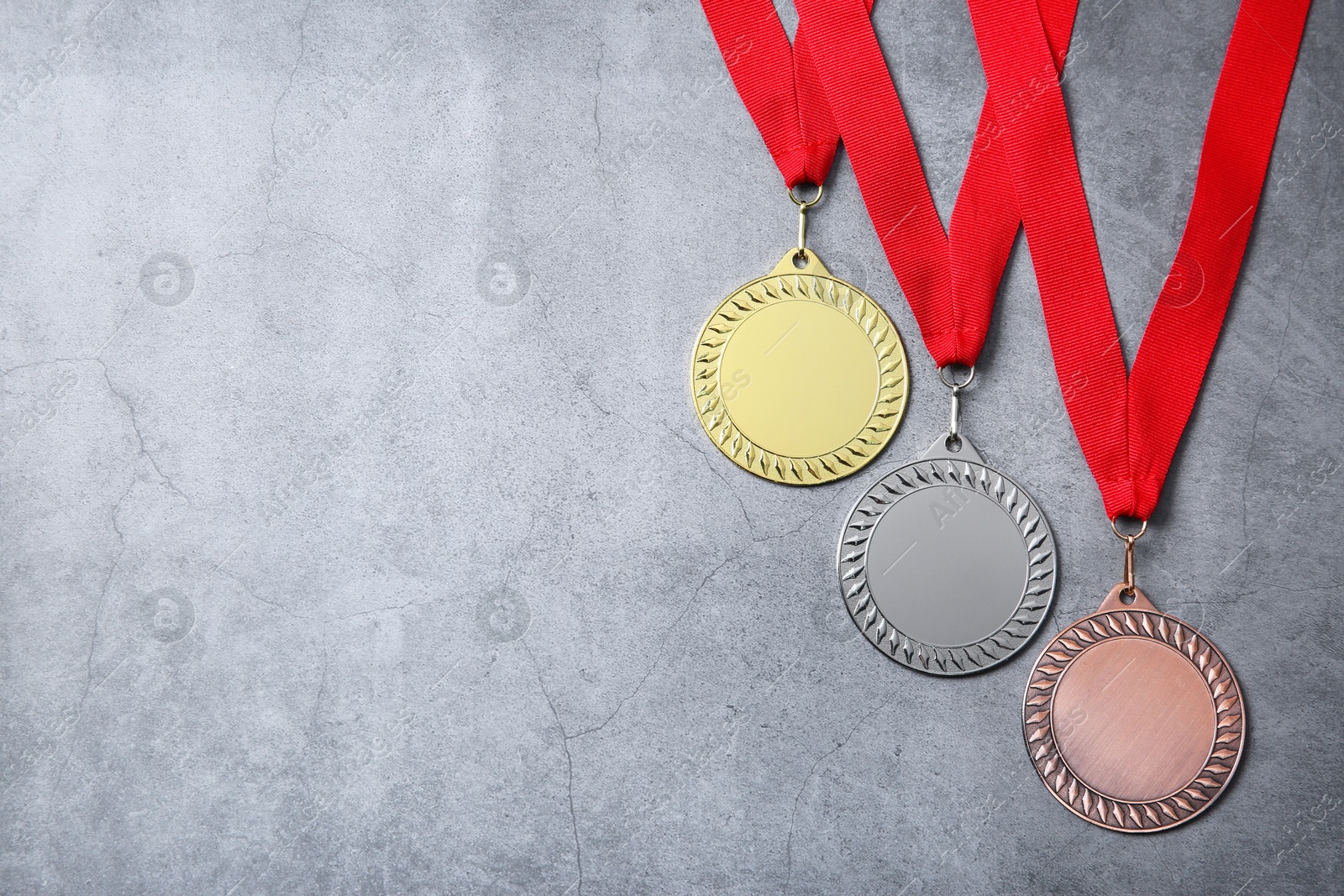 Photo of Golden, silver and bronze medals on grey background, top view. Space for text