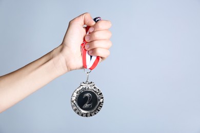 Photo of Woman with silver medal on grey background, closeup. Space for text