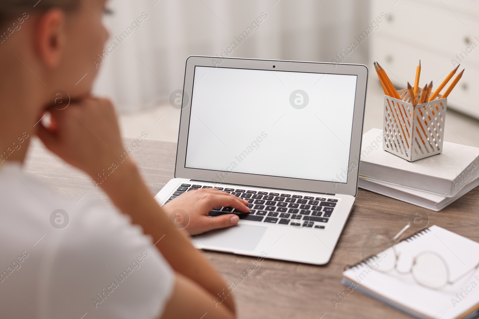 Photo of Woman working with laptop at wooden table in office, closeup. Mockup for design