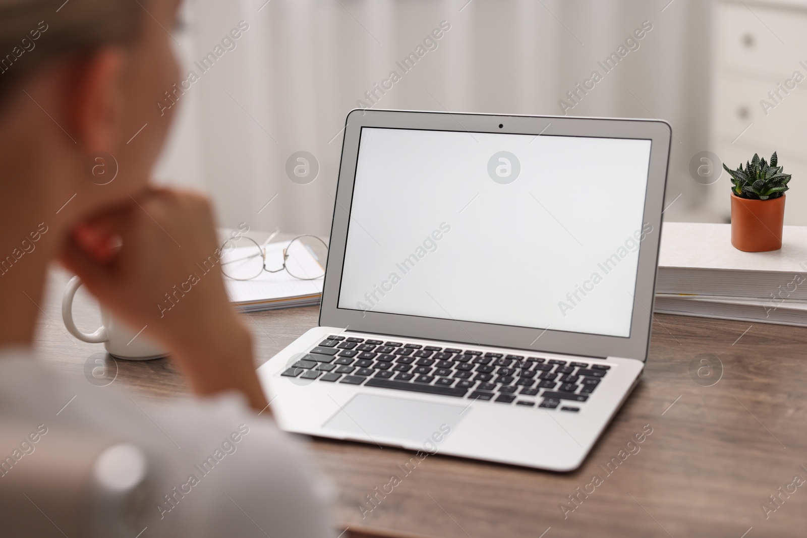 Photo of Woman working with laptop at wooden table in office, closeup. Mockup for design