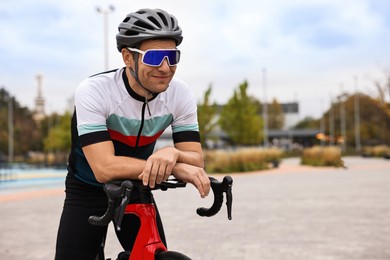 Photo of Athletic man with helmet and bicycle outdoors, space for text