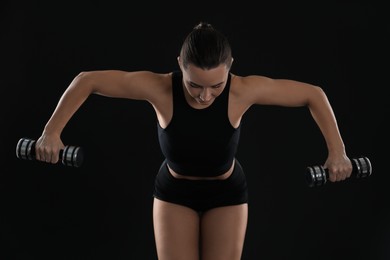 Photo of Woman exercising with dumbbells on black background