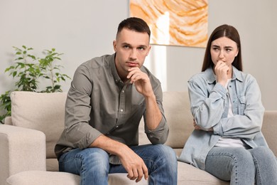 Photo of Husband ignoring his wife on sofa at home