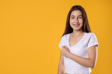 Photo of Woman making promise on orange background, space for text. Oath gesture