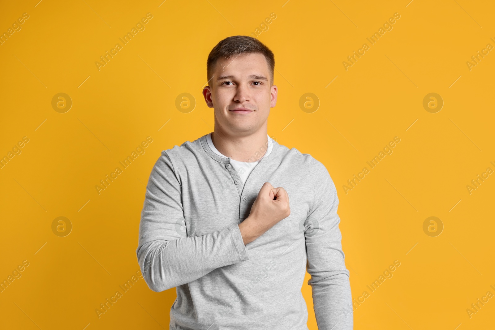 Photo of Man making promise on orange background. Oath gesture