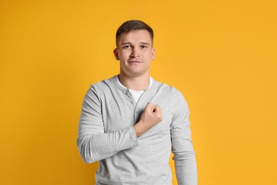 Photo of Man making promise on orange background. Oath gesture