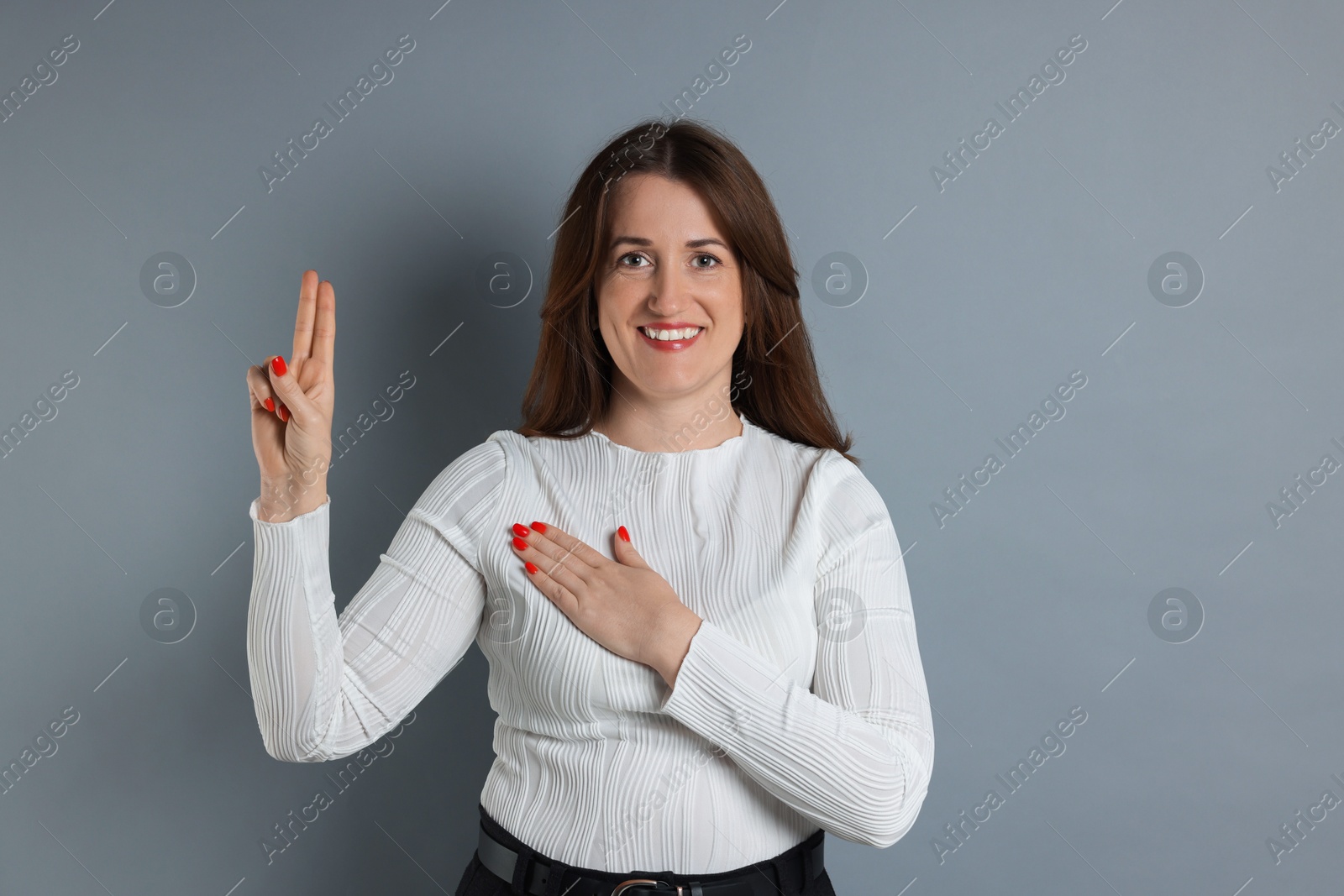 Photo of Woman showing oath gesture on grey background. Making promise