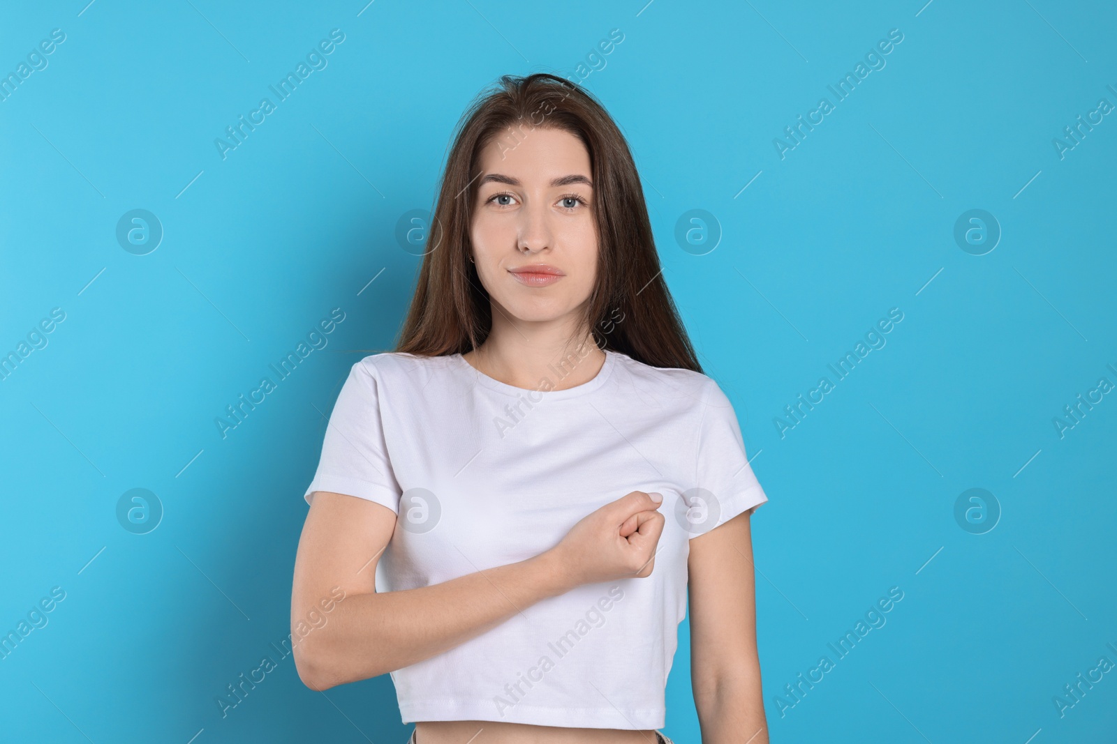 Photo of Woman making promise on light blue background. Oath gesture