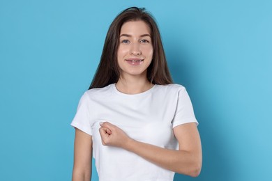 Photo of Woman making promise on light blue background. Oath gesture