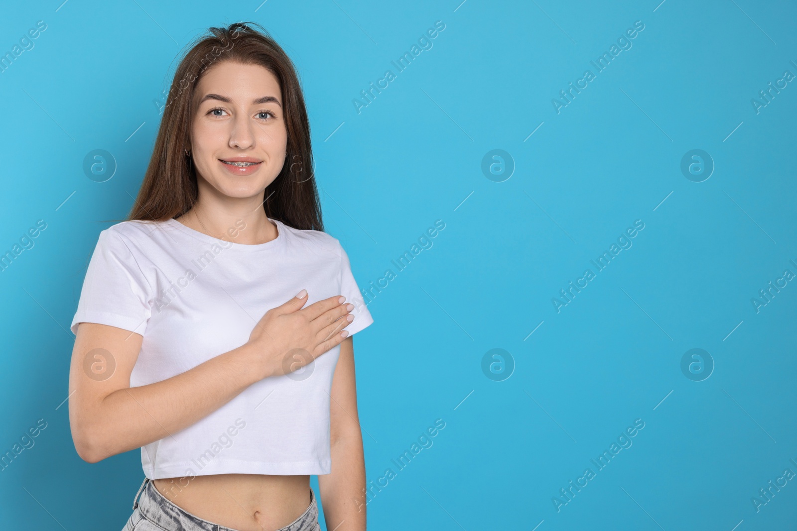 Photo of Woman making promise on light blue background, space for text. Oath gesture