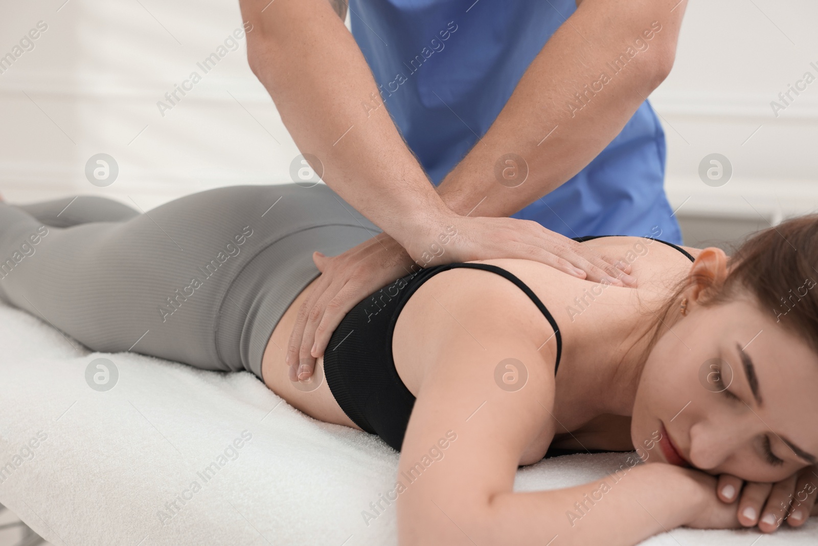 Photo of Osteopath massaging woman's back on couch indoors, closeup. Manual therapy