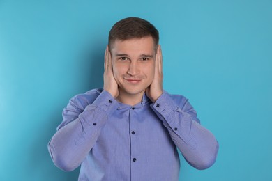 Photo of Man covering his ears on light blue background