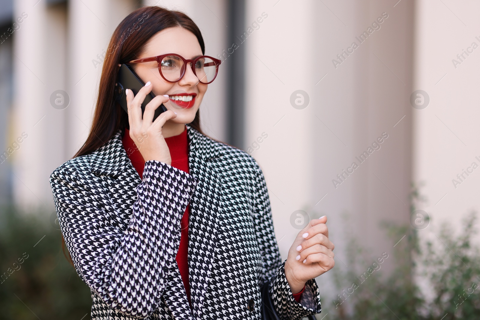 Photo of Beautiful woman in stylish suit talking on smartphone outdoors. Space for text