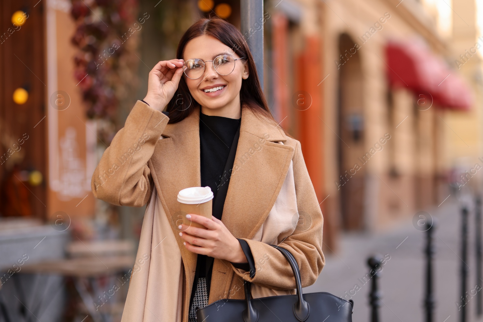 Photo of Smiling businesswoman in stylish outfit with paper cup outdoors. Space for text