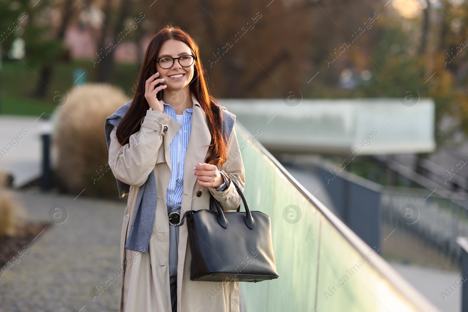 Photo of Beautiful woman in stylish suit talking on smartphone outdoors. Space for text