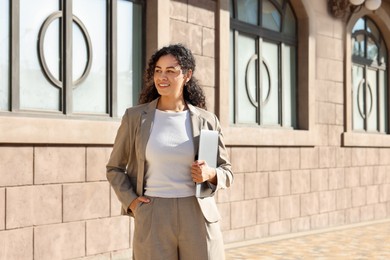 Photo of Portrait of young woman with laptop wearing stylish suit outdoors