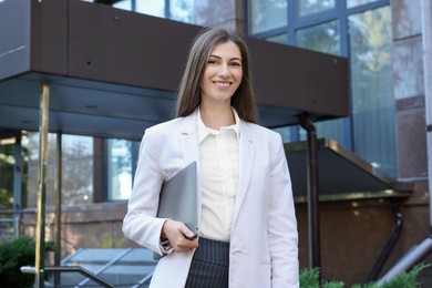 Photo of Portrait of young woman with laptop wearing stylish suit outdoors