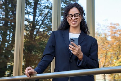 Photo of Portrait of young woman with phone wearing stylish suit outdoors