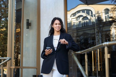 Photo of Portrait of young woman with phone wearing stylish suit outdoors