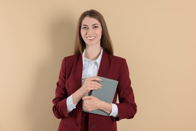 Portrait of smiling banker with book on beige background