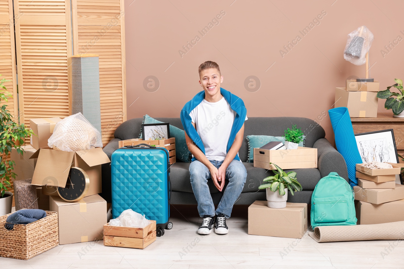 Photo of Happy man with different stuff in new apartment. Housewarming party