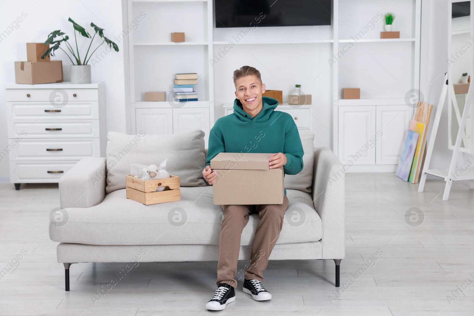 Photo of Happy man with moving boxes in new apartment. Housewarming party