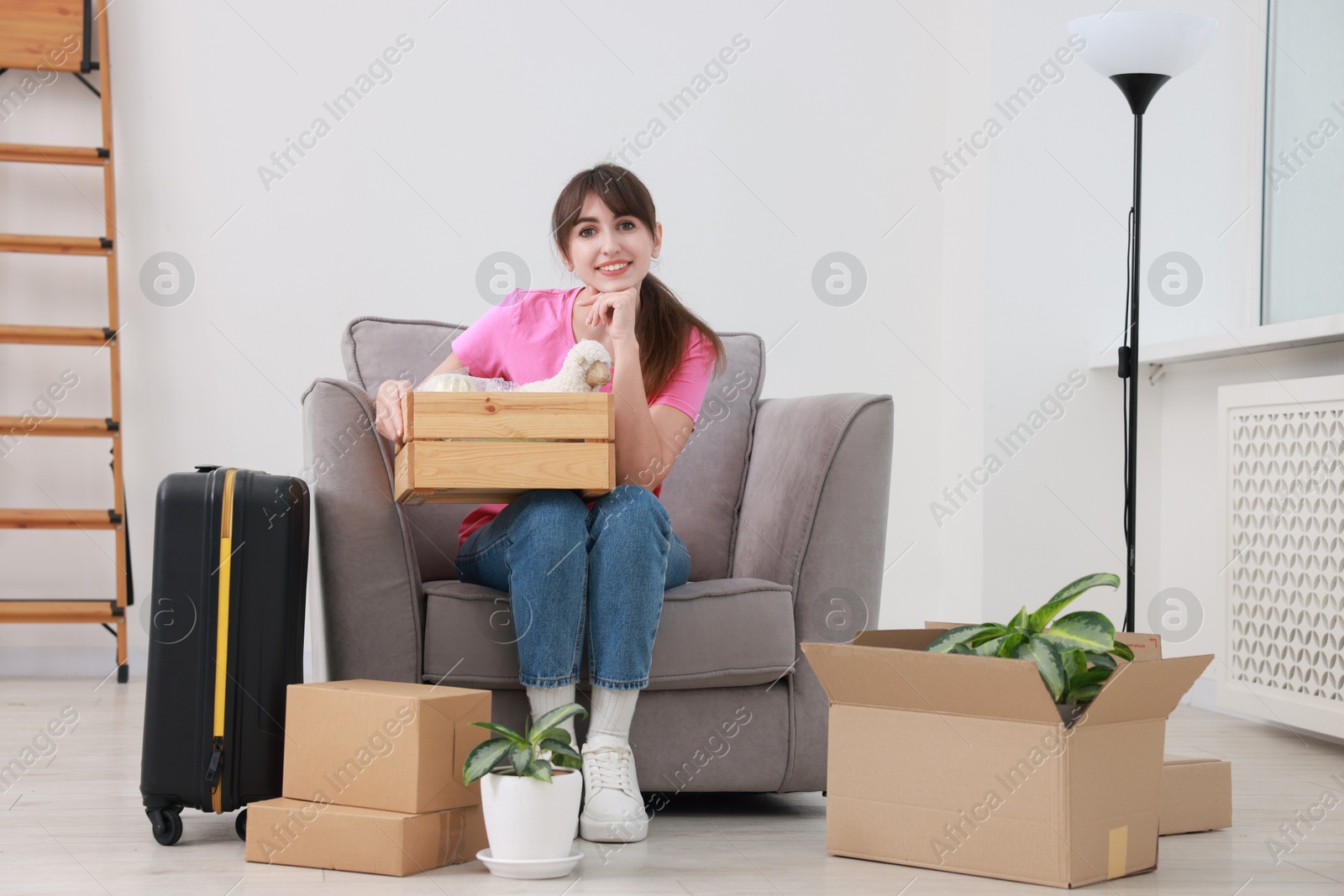 Photo of Happy woman with different stuff in new apartment. Housewarming party