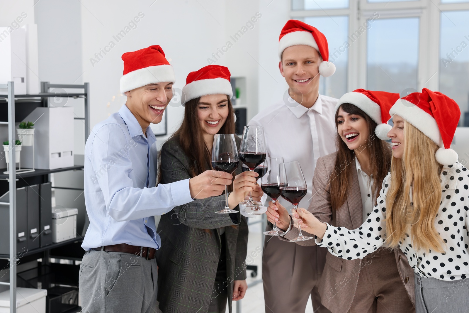 Photo of Happy coworkers clinking glasses of wine during office Christmas party