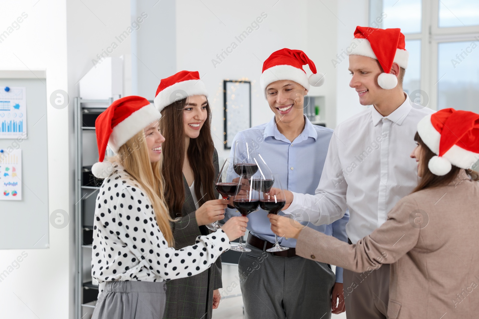 Photo of Happy coworkers clinking glasses of wine during office Christmas party