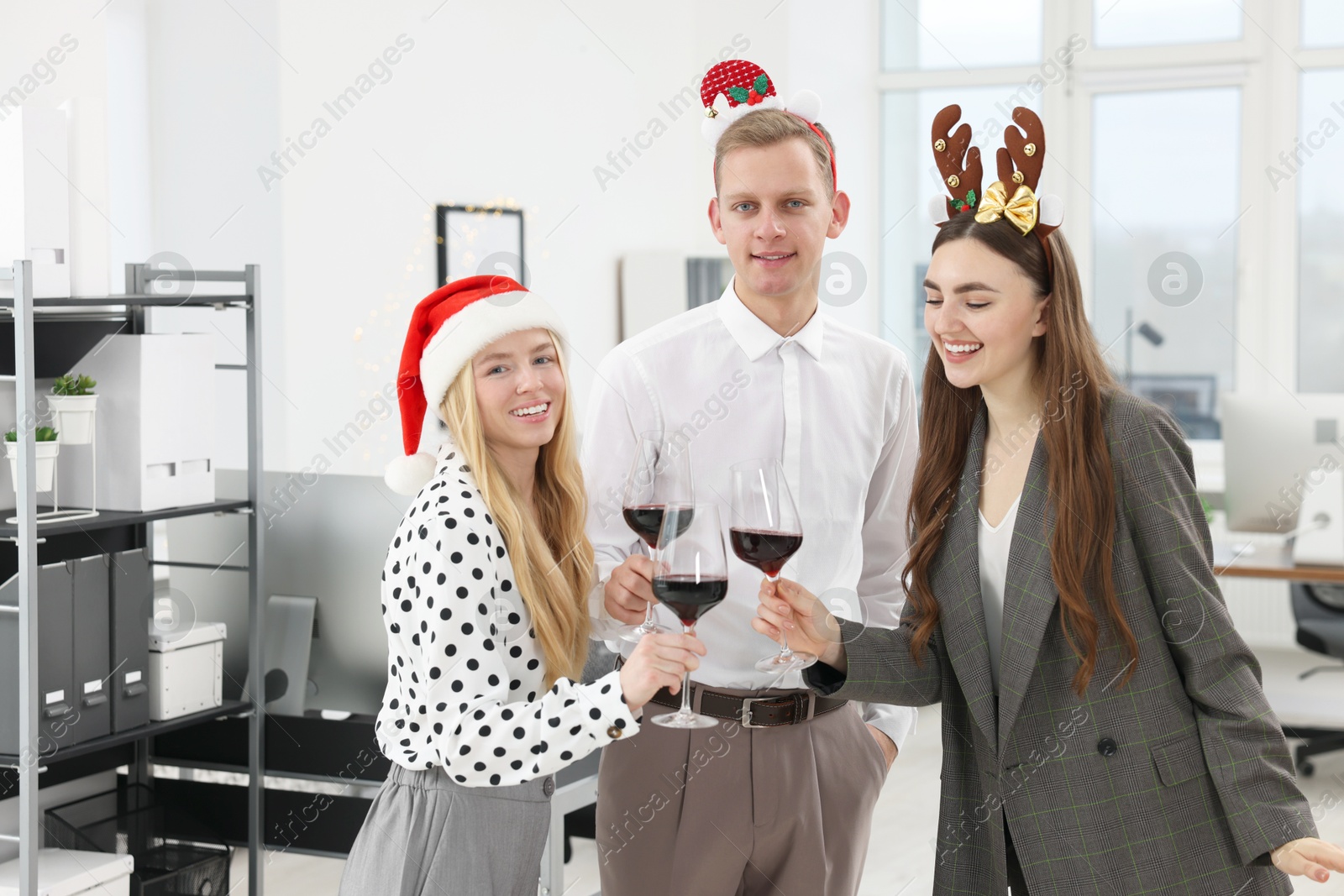 Photo of Happy coworkers clinking glasses of wine during office Christmas party