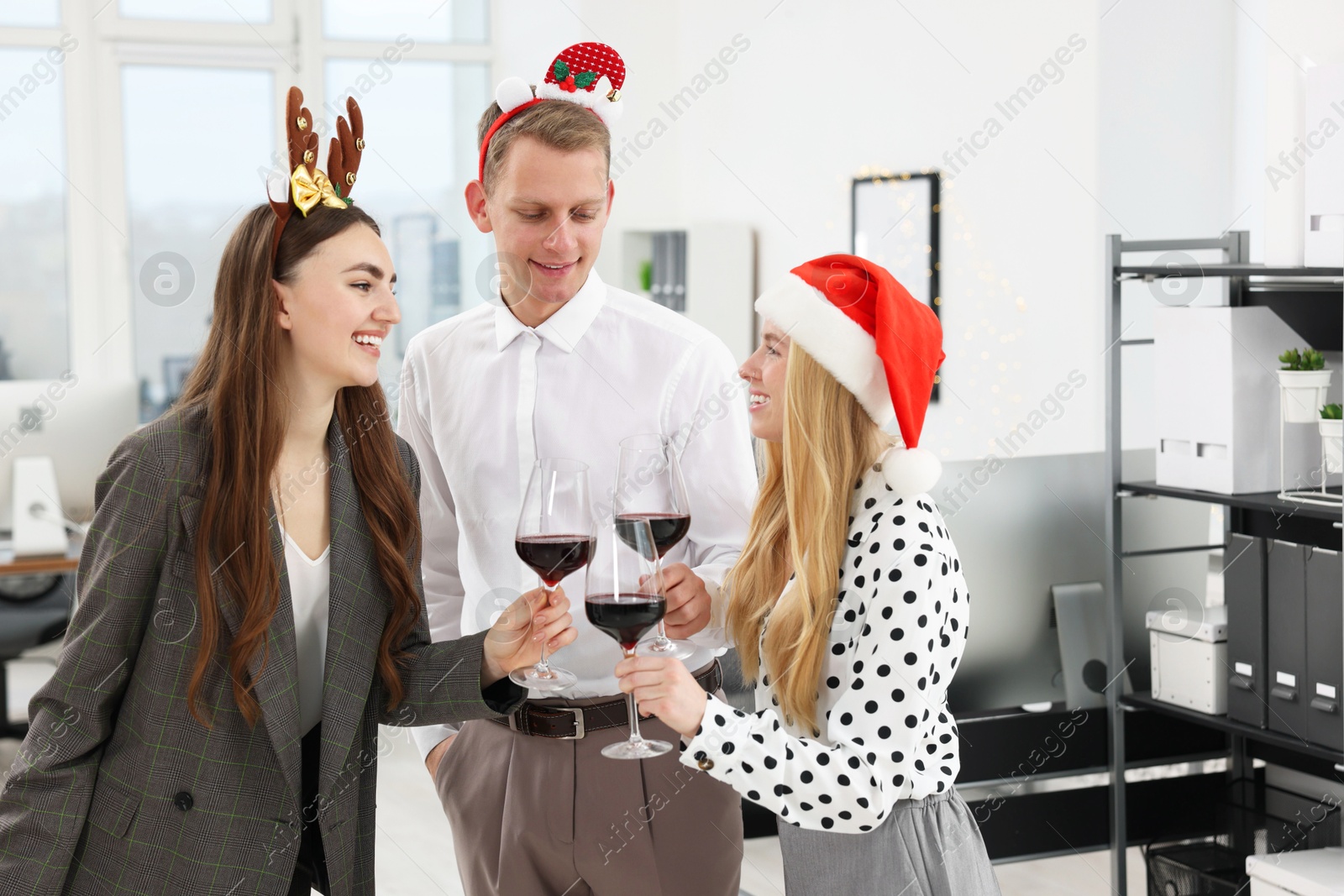 Photo of Happy coworkers clinking glasses of wine during office Christmas party