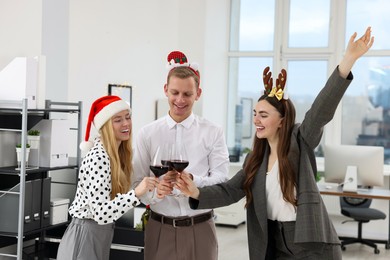 Photo of Happy coworkers clinking glasses of wine during office Christmas party