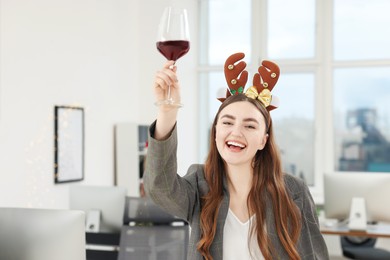 Cheerful woman with glass of wine having fun at office Christmas party