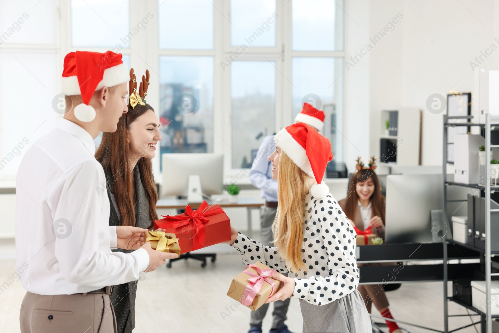 Photo of Happy coworkers exchanging gifts at office Christmas party