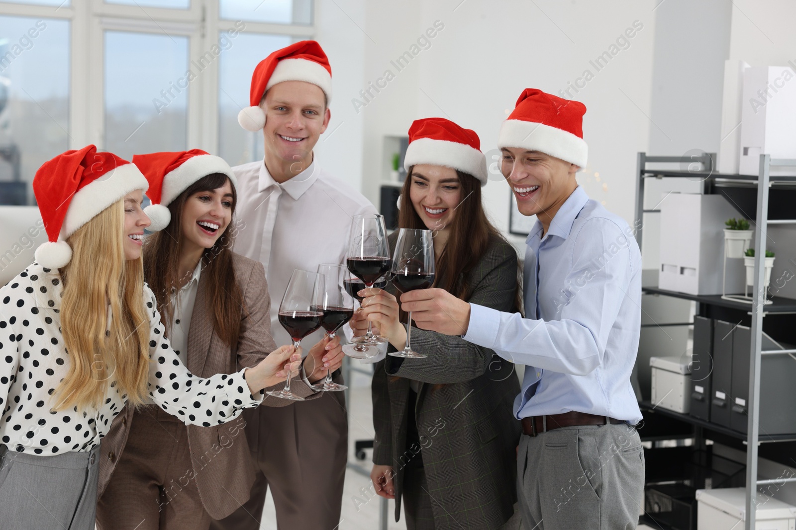 Photo of Happy coworkers clinking glasses of wine during office Christmas party