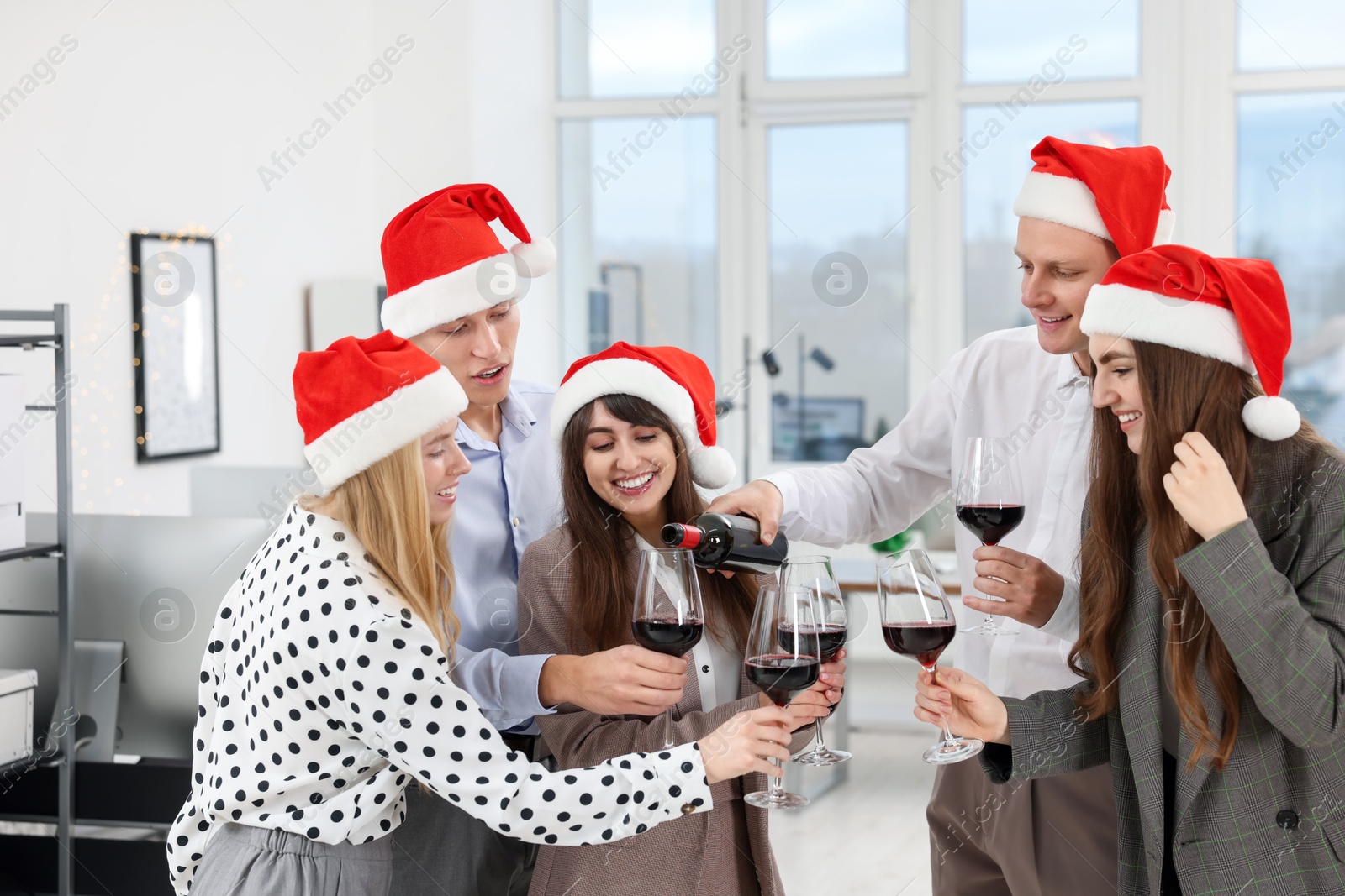 Photo of Man pouring wine for his colleagues at office Christmas party