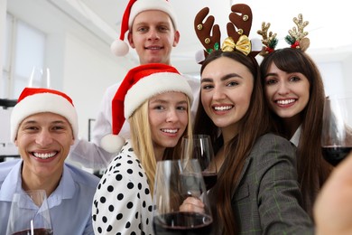 Photo of Smiling colleagues taking selfie at Christmas party in office