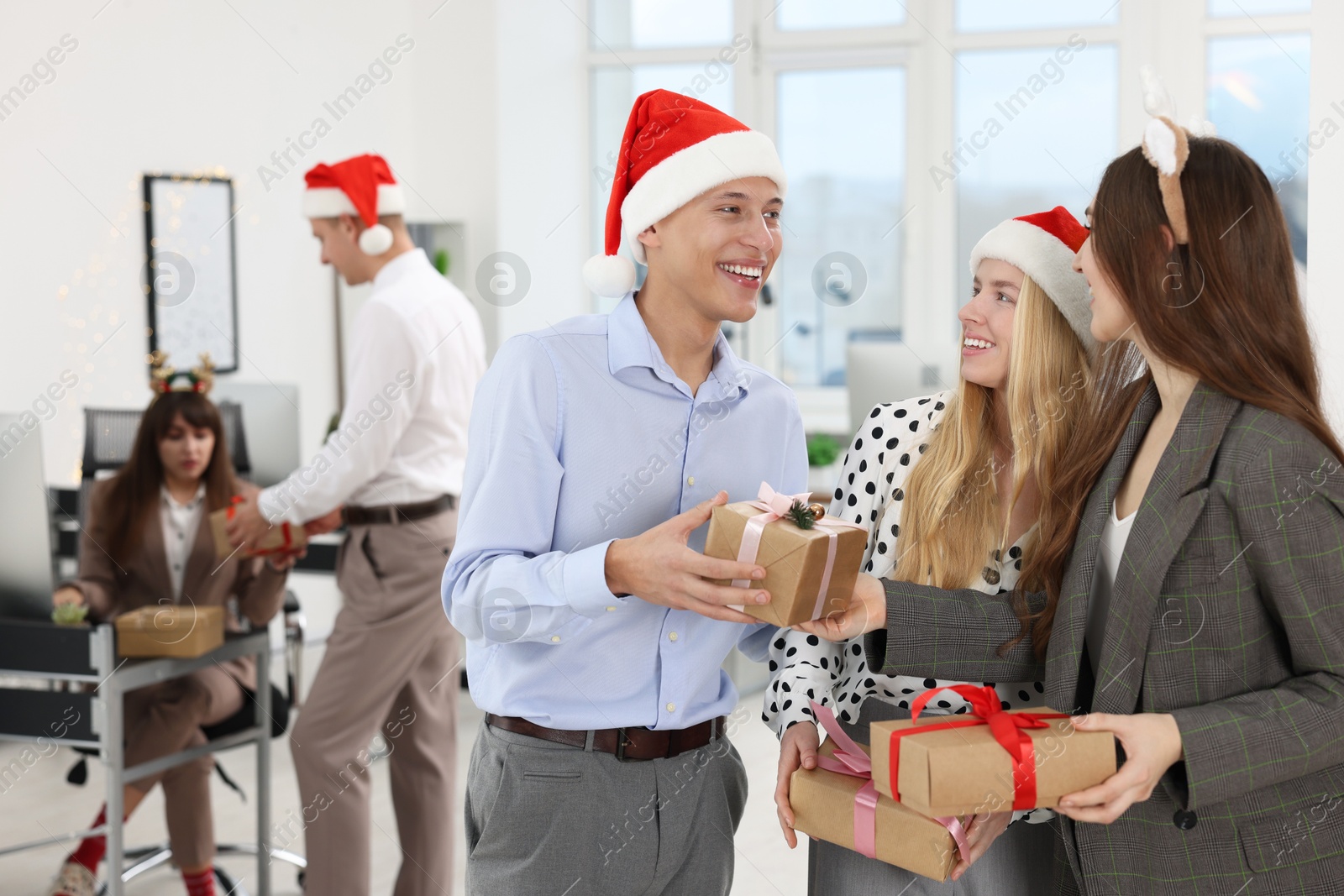 Photo of Happy coworkers exchanging gifts at office Christmas party