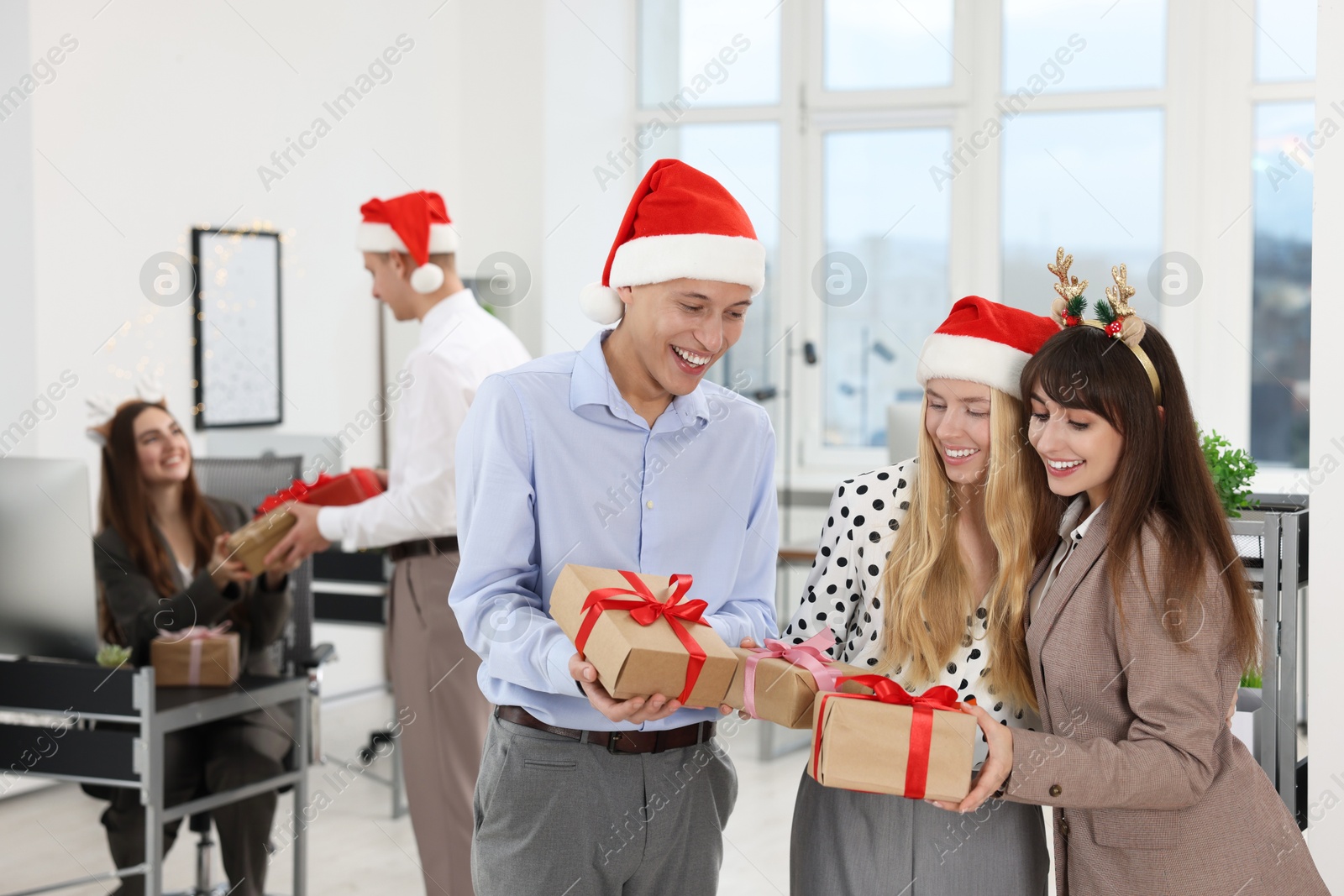 Photo of Happy coworkers exchanging gifts at office Christmas party