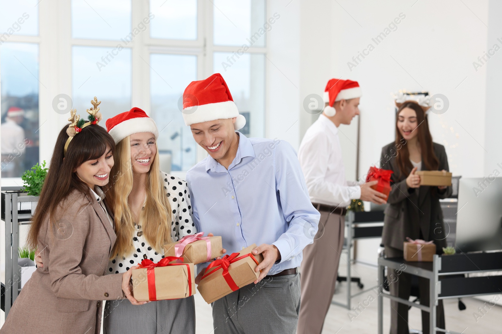 Photo of Happy coworkers exchanging gifts at office Christmas party